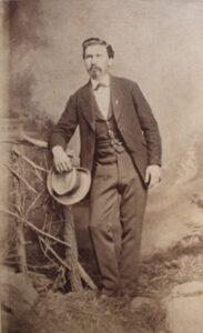 RJ Reynolds' eldest brother, Abram Reynolds wearing a suit and holding a hat in a sepia toned photo.