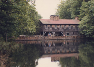 Dick and Blitz Reynolds' wooden home is pictured next to a lake surrounded by trees.